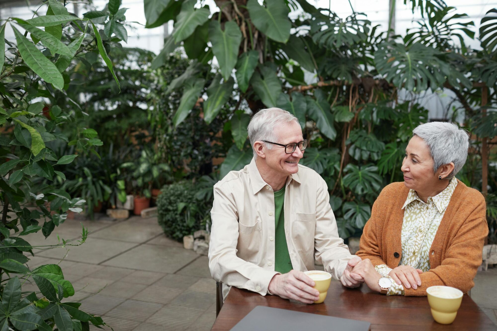 Joyful senior couple sharing a tender moment over coffee in a lush green garden.